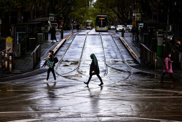 Woman walking alone on Melbourne street with tram in background