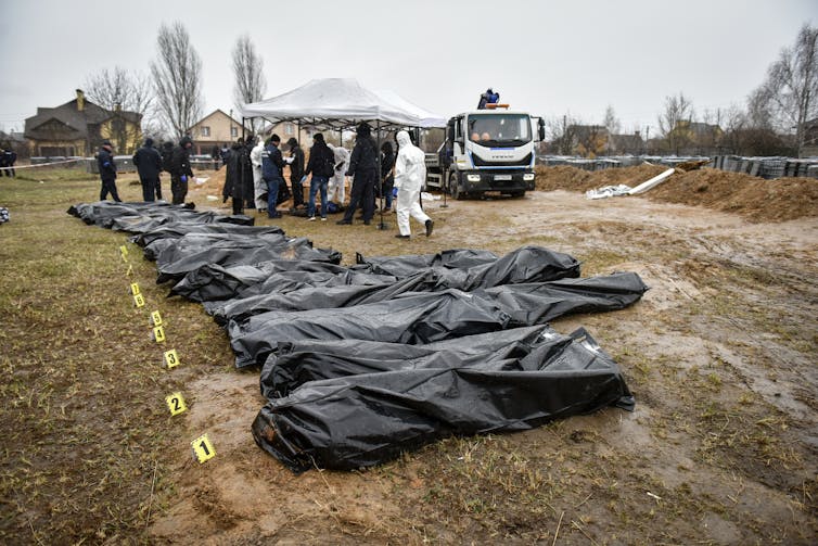 Forensic investigators line up a row of corpses in body bags, Bucha, April 2022.