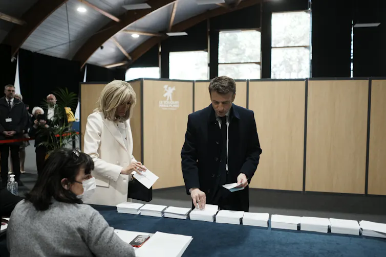 Emmanuel Macron at a polling station picking up his ballot papers in order to vote.