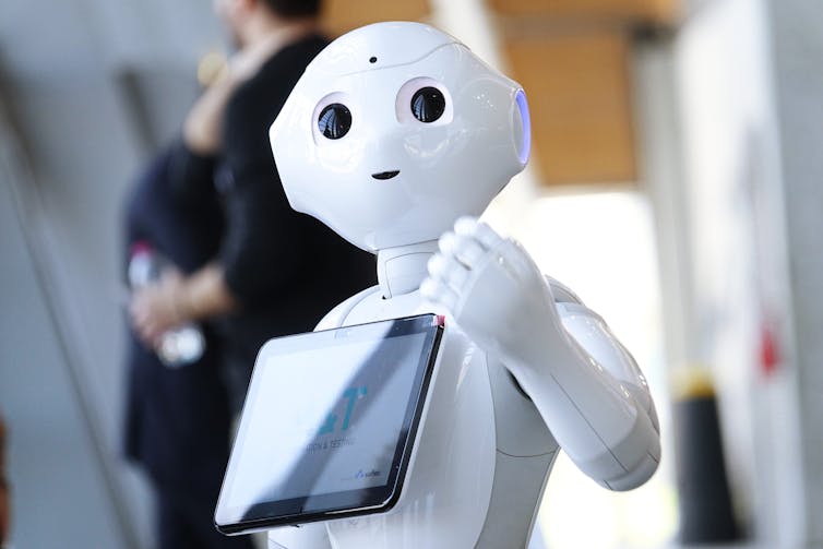 A robot assistant holds a tablet.
