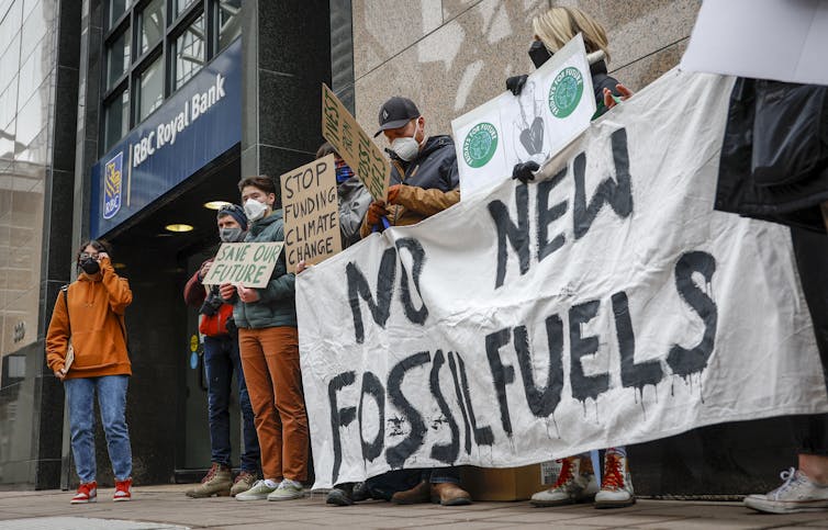 Demonstrators seen outside a Royal Bank branch with a sign 'no new fossil fuels.'