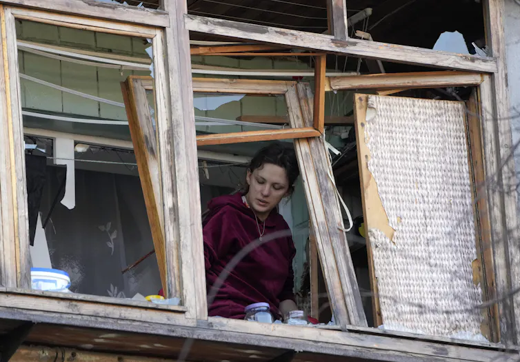 Une femme à la fenêtre d’un immeuble détruit