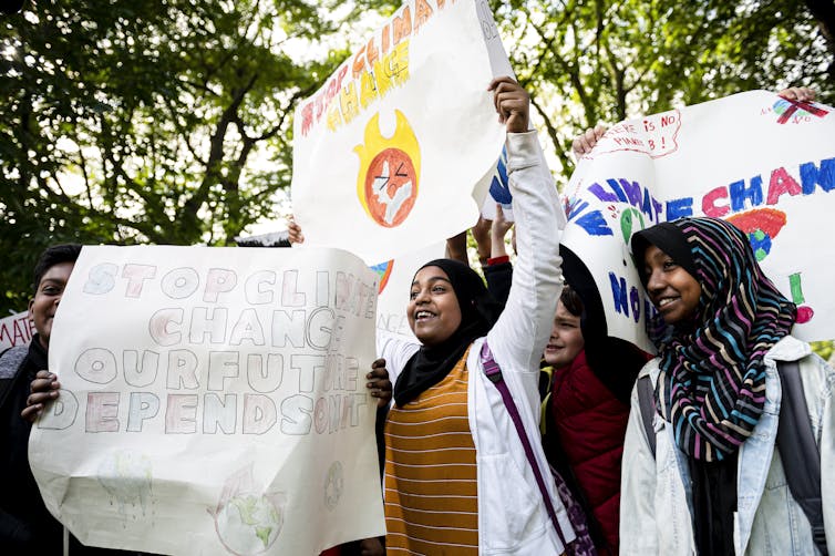 Students are seen carrying posters at a rally, one saying 'stop climate change, our future depends on it.