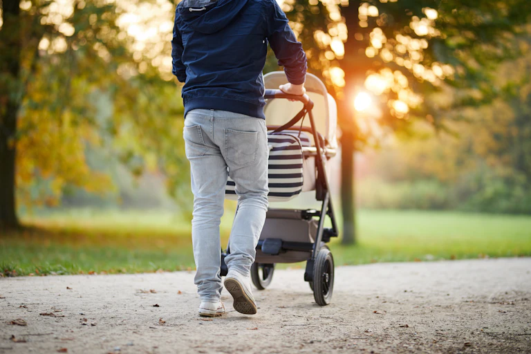 man pushing pushchair in park