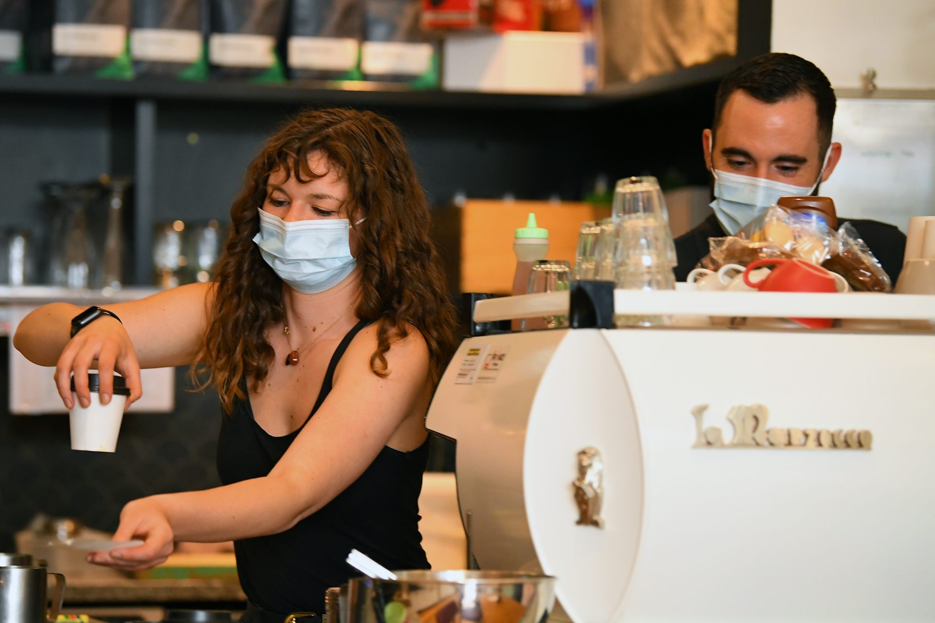 Two young baristas making coffee in a cafe
