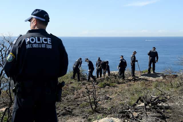 police on the edge of a cliff, conducting a search