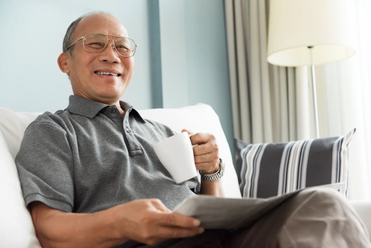 Old man sitting on couch and smiling.