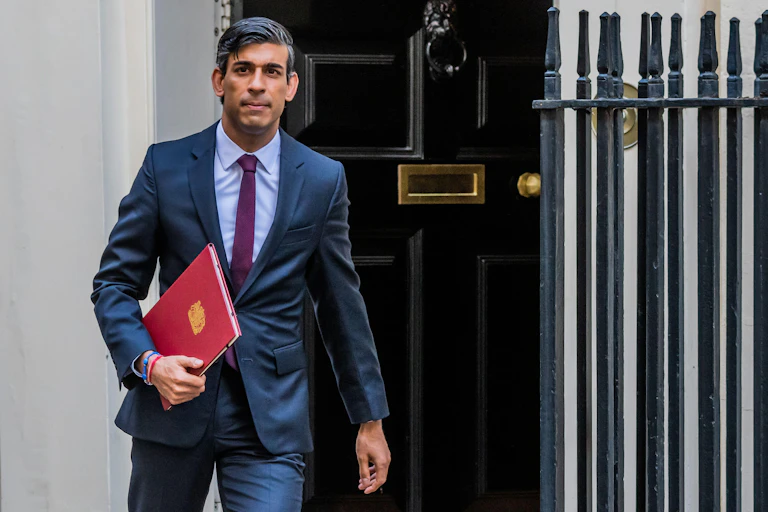 Rishi Sunak leaves Downing Street while carrying a red folder and looking serious
