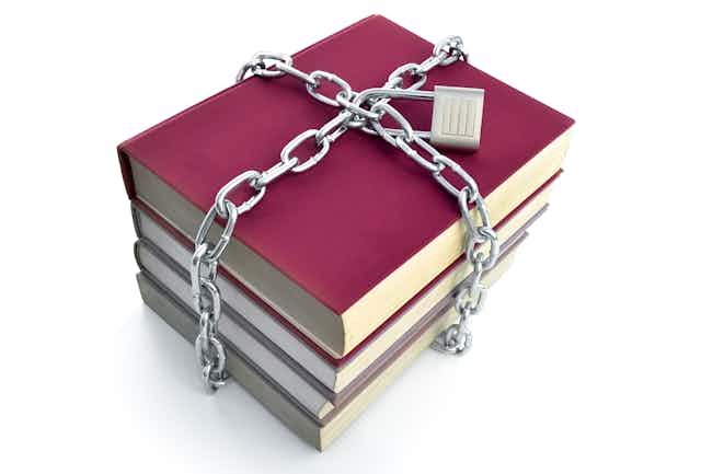Four books, held together with a chain and a lock on the chain.