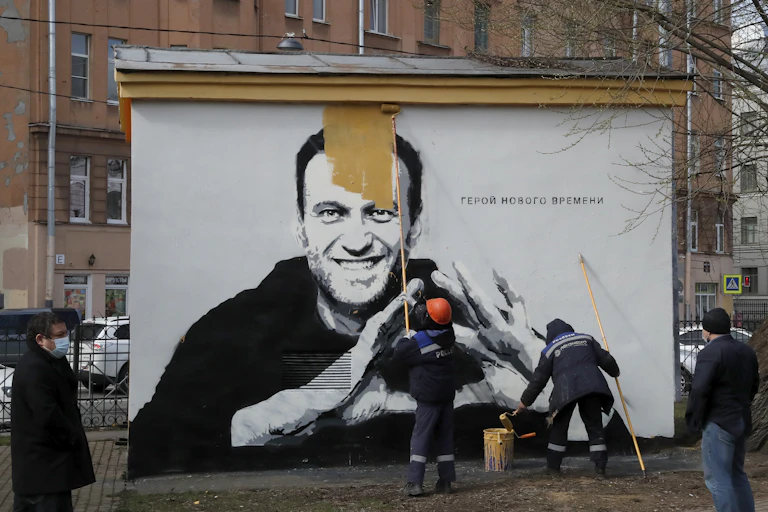 Russian council workers paint over a poster of Russian opposition figure Alexei Navalny.
