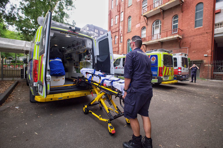 Paramedic pushing bed into the back of an ambulance