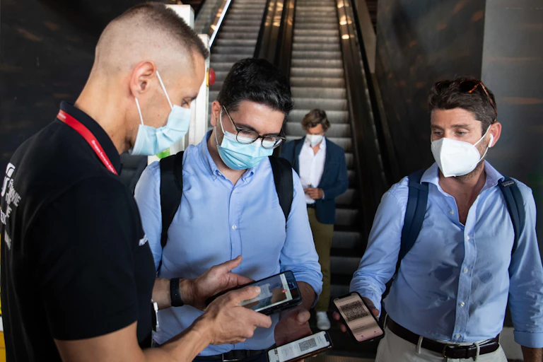 Men showing their phones with vaccine passports to a security guard