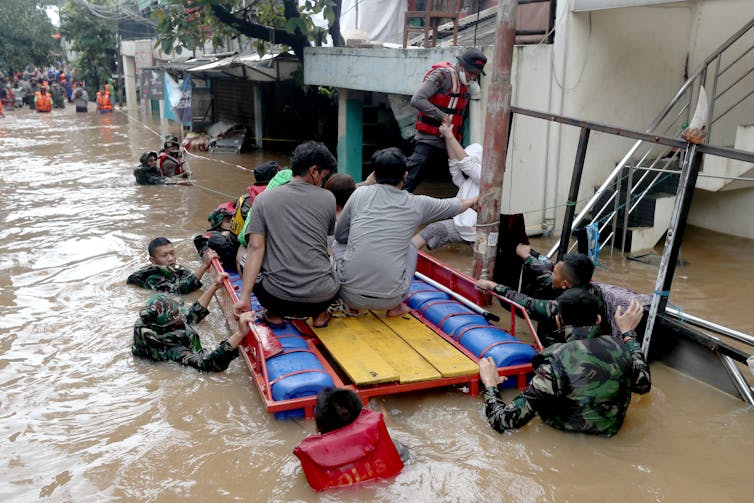 People on a makeshift raft during flooding in Jakarta.