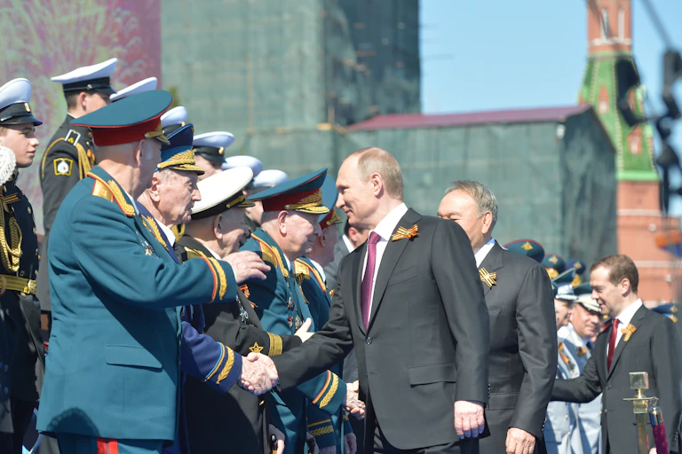 Vladimir Putin and other dignatories shake hands with Russian veterans during a parade in Red Square, Moscow, 2016