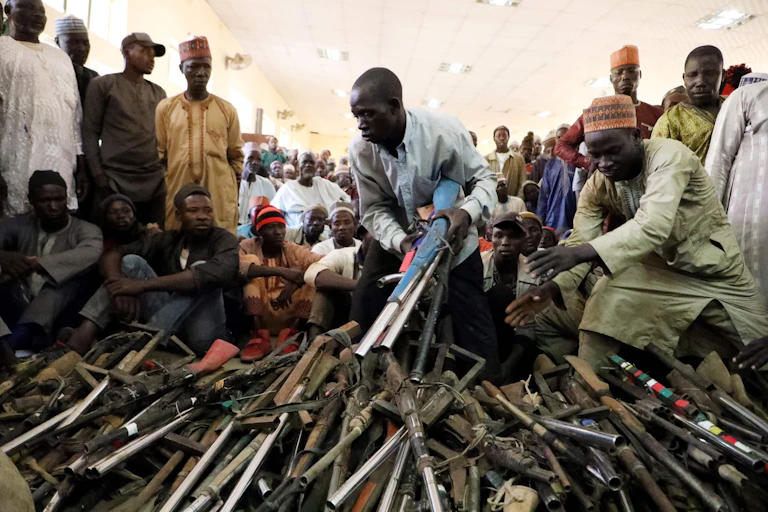 Men pilling up guns while others look