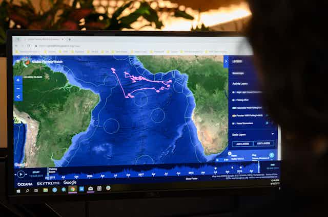 On a computer screen, pink dots in the eastern Atlantic record the movement of fishing vessels