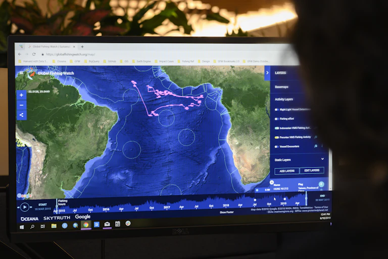 On a computer screen, pink dots in the eastern Atlantic record the movement of fishing vessels