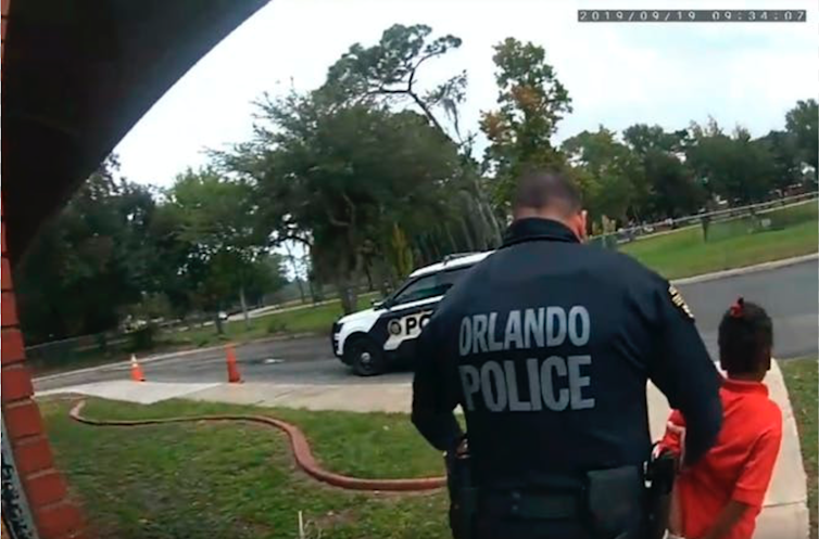 An Orlando city police officer handcuffs a young Black child.