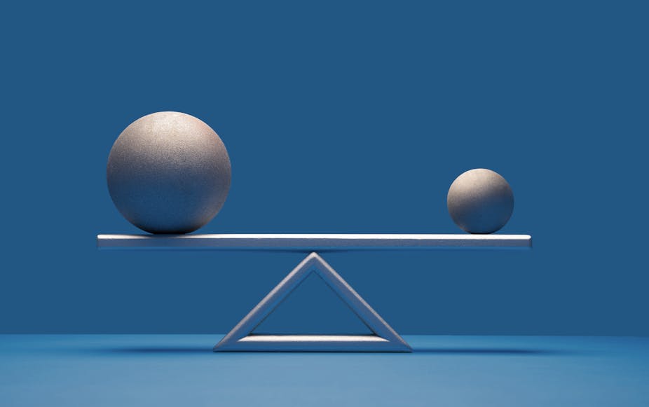 Two balls of different sizes equally balanced on a scale.