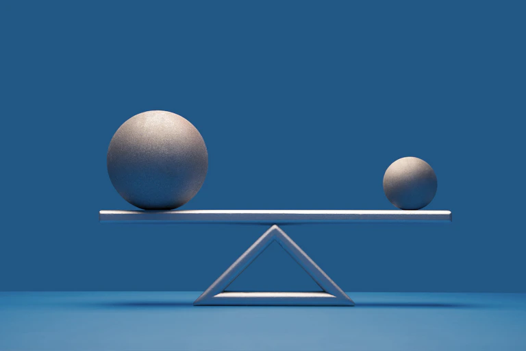 Two balls of different sizes equally balanced on a scale.