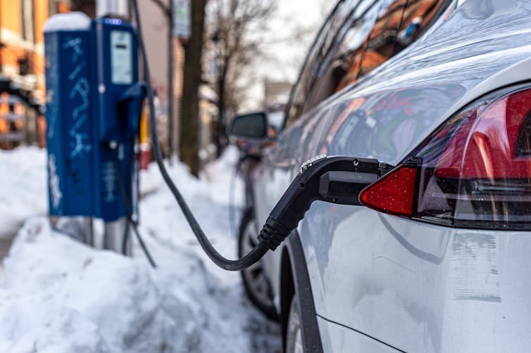 A car charges on a snowy street at a public charger