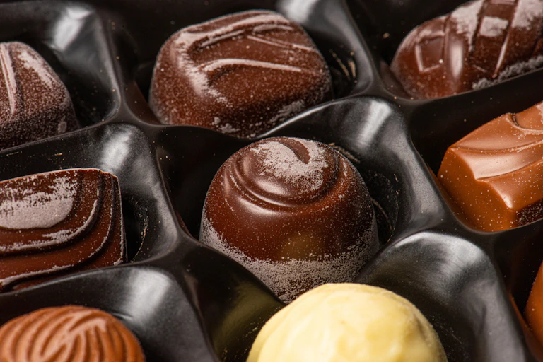 Chocolate pieces in tray with a white film of bloom on them