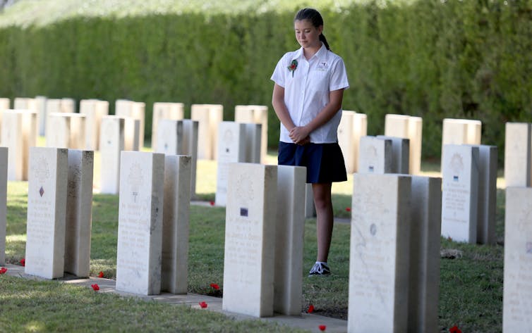 A schoolgirl standing in a military cemetery, reflecting on the sacrifice of WWI soldiers