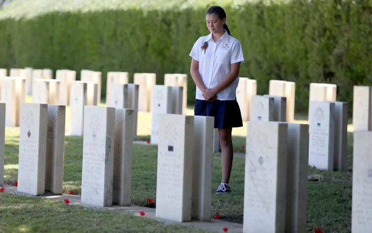 A schoolgirl standing in a military cemetery, reflecting on the sacrifice of WWI soldiers