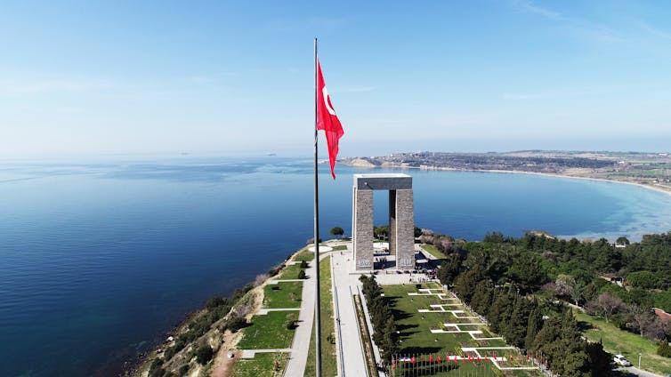 An aerial view of the Gallipoli National Park in Turkey, positioned behind a flagpole bearing the Turkish national flag