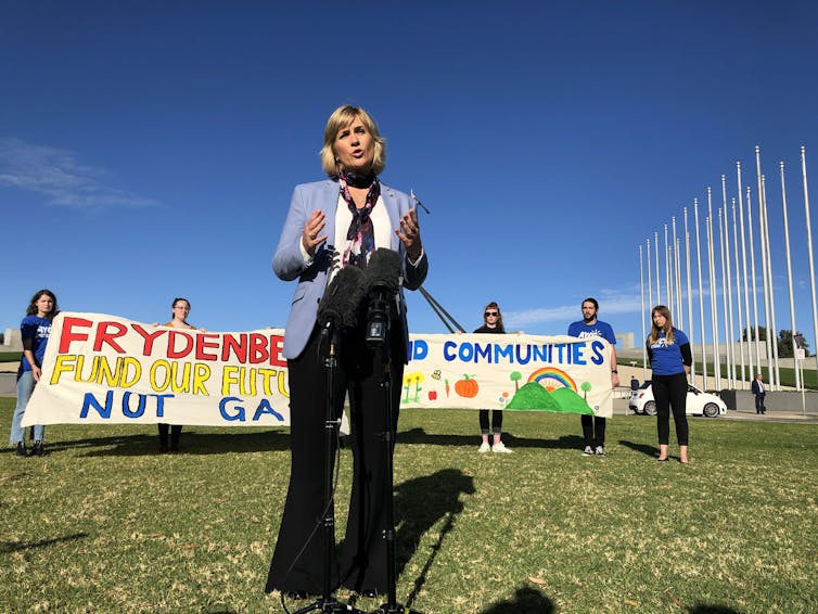 woman stands in fornt of climate protest signs