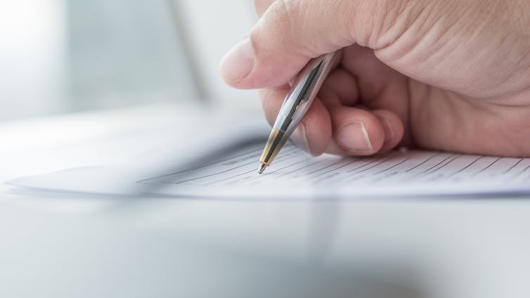 View of a hand filling out a paper form