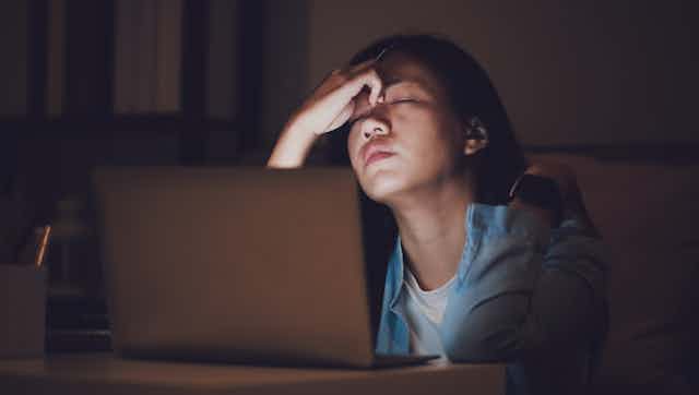 Woman tired at computer in dark
