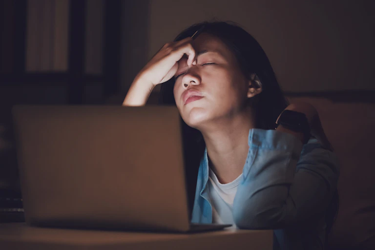 Woman tired at computer in dark