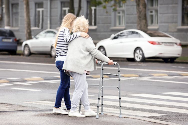 Young woman helps older woman cross the road
