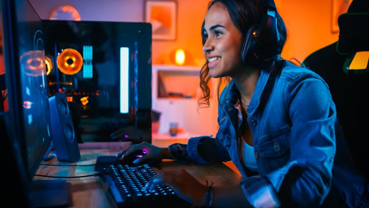 A young woman playing a video game, smiling and enjoying herself.