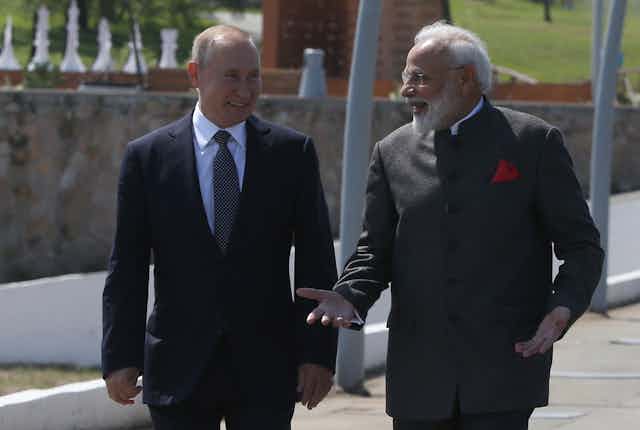 Vladimir Putin and Narendra Modi chat as they walk in the sunshine.