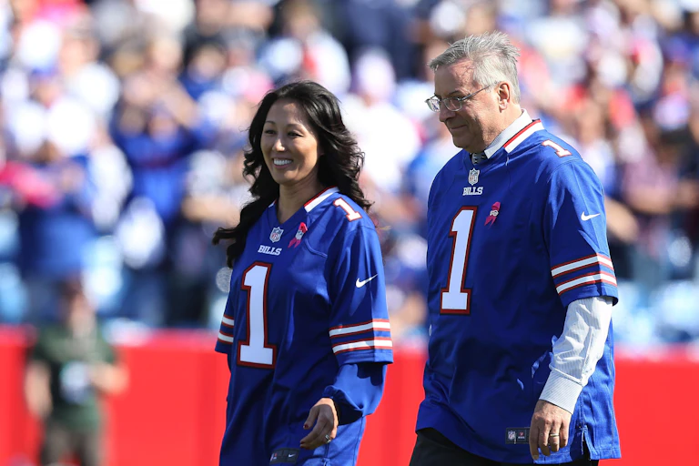 Woman and man wearing blue football jerseys.