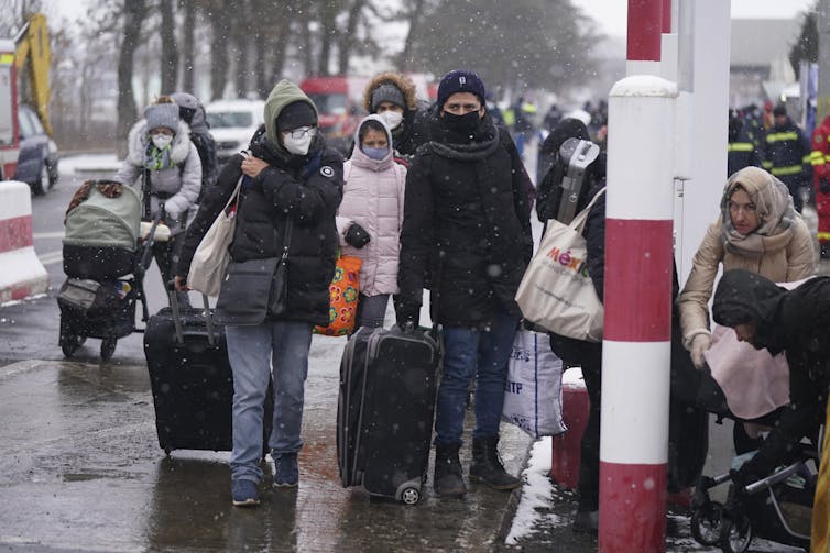 Un groupe de personnes, portant des valises, marchent dans une rue