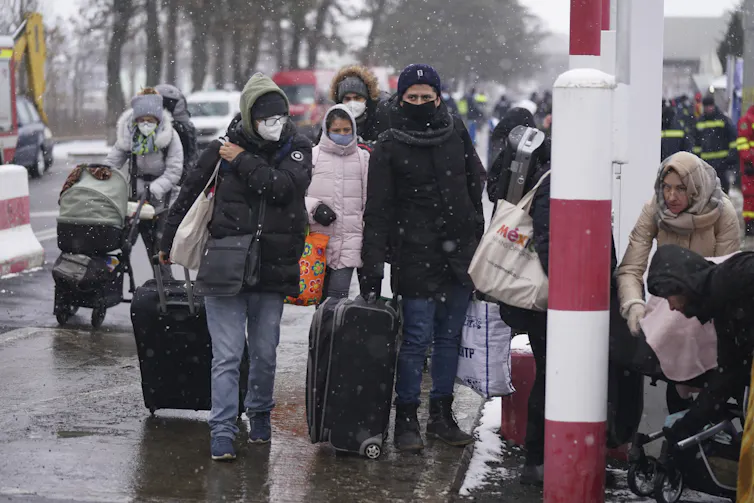 Un groupe de personnes, portant des valises, marchent dans une rue