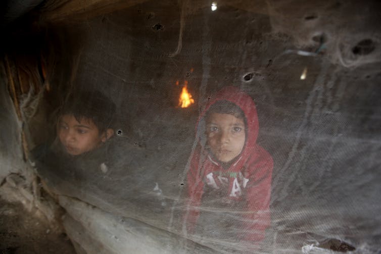 Deux enfants vus à travers un rideau de plastique