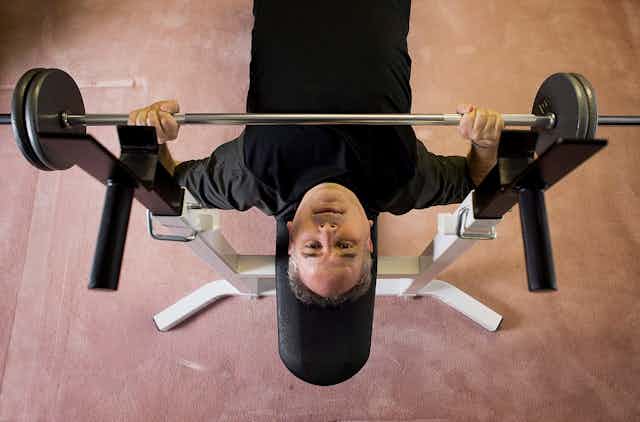 A man doing bench presses on a weight bench