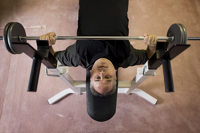 A man doing bench presses on a weight bench