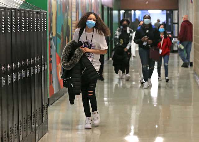 High school students walk down a hallway.