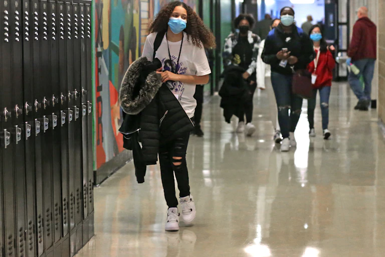 High school students walk down a hallway.