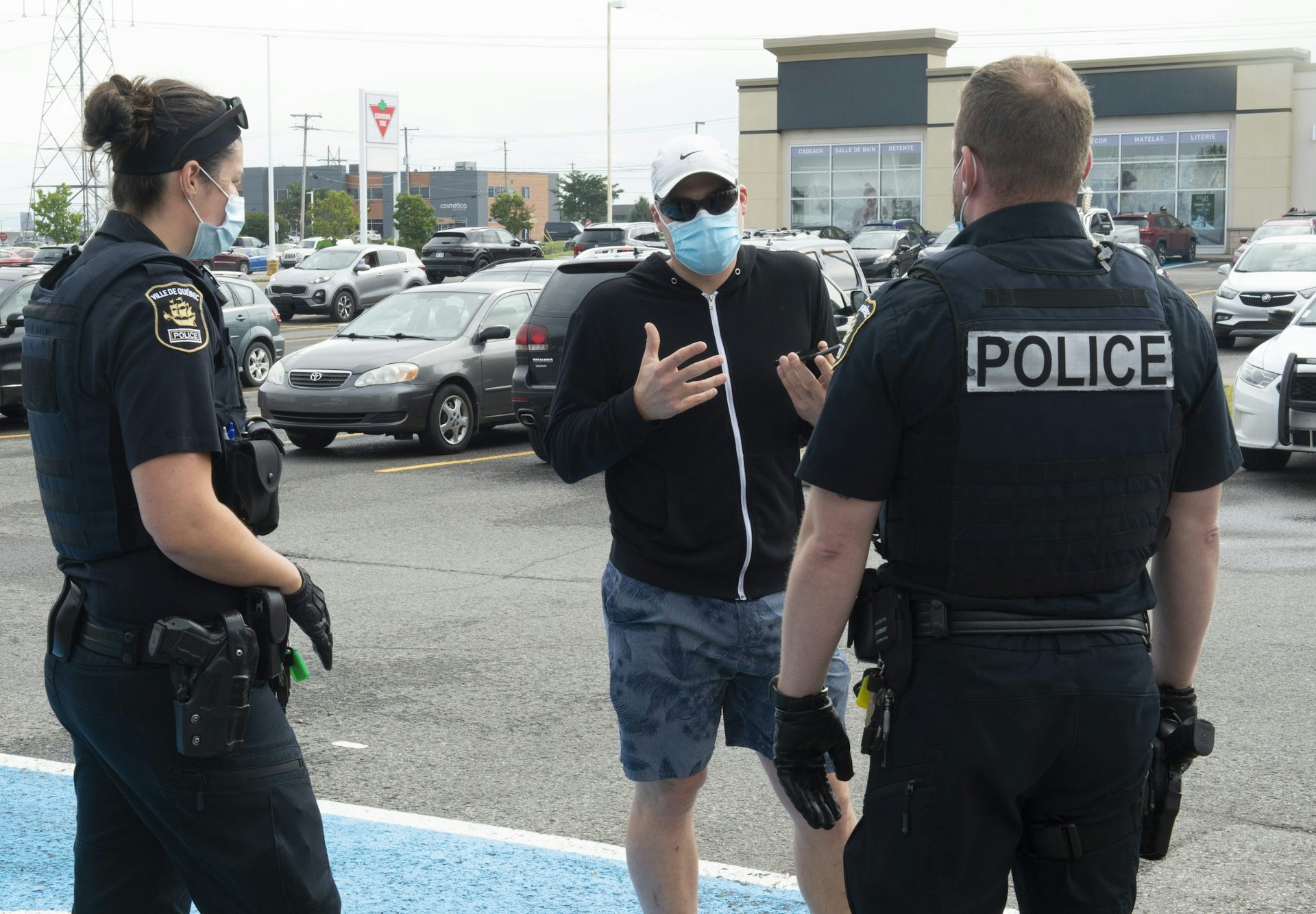 Deux policiers encadrent un homme portant un masque