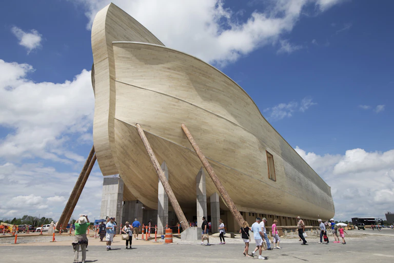 Visitors walking outside a giant replica of Noah's Ark, which has stairs on either side, in Williamstown, Kentucky.