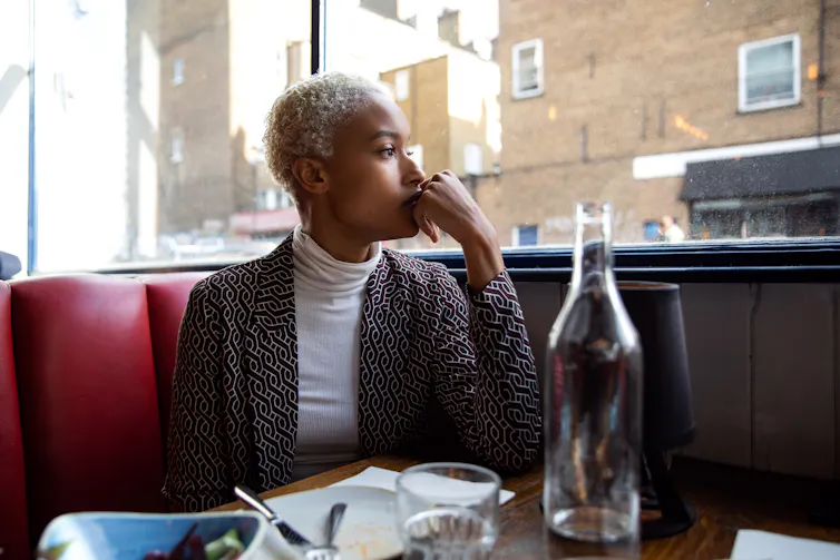 woman seated in restaurant booth looks out the window pensively