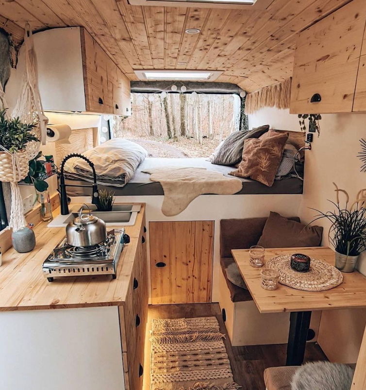 The custom interior of a #vanlife van with designer kitchen, seating area, and bed.
