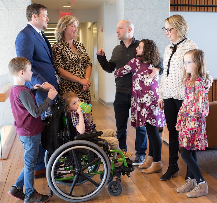 Two families, each of whom has a child with a rare genetic disease, stand facing one another and smiling.