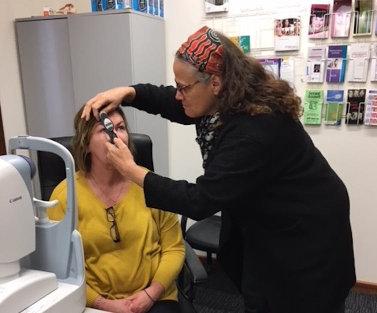 woman checks eyes of a second woman